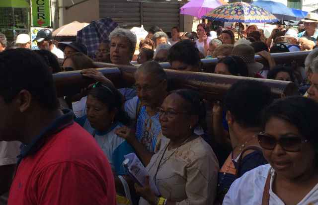 Homens e mulheres participam do cortejo revezando-se a carregar uma cruz de madeira com mais de 100 quilos. Foto: Henrique Souza