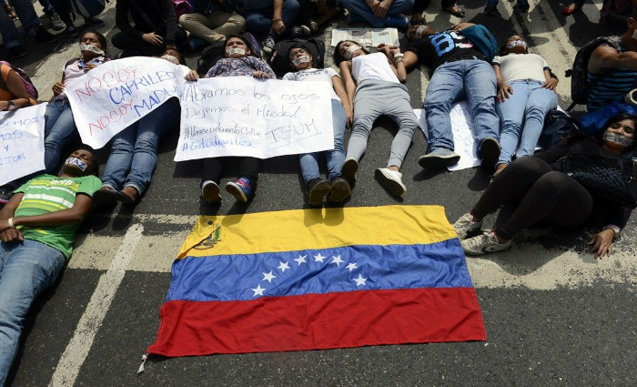 Jovens se deitam no cho em protesto contra mortes na Venezuela Foto: Leo Ramirez/AFP Photo