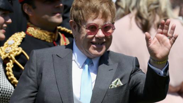 Ele ostentava um ousado par de culos rosa quando chegou com o marido David Furnish. Foto: AFP/Reproduo