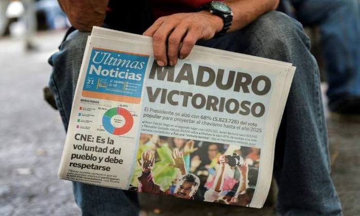 Homem com jornal que anuncia vitria do reeleito presidente Nicols Maduro nas presidenciais venezuelanas em Caracas
(foto: Luis Robayo/AFP )