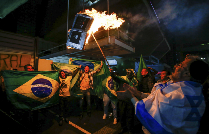 Eleitores de Bolsonaro incendiando urna eletrnica: candidato  presidncia questionou diversas vezes a confiabilidade do equipamento. Foto: Alexandre Schneider/AFP 