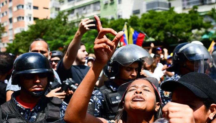 Apoiadores FR Juan Guaid protestam diante de uma fila de oficiais da Polcia Nacional Bolivariana em Caracas, neste sbado. Foto: RONALDO SCHEMIDT/AFP Photo 