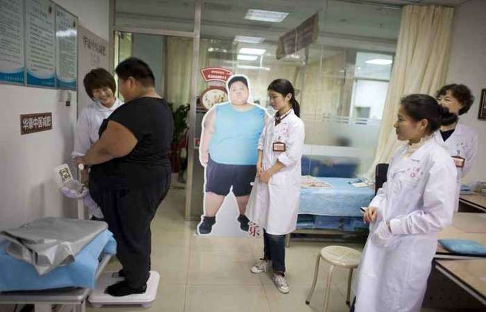 Observado por profissionais de sade, adolescente chins se pesa em um consultrio de Pequim: demonstrao de afeto  determinante para o paciente. foto: Alain Jocard/AFP - 12/4/19 