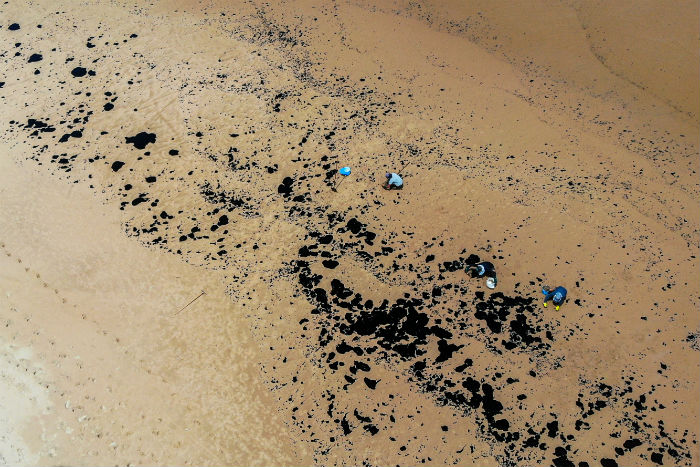Manchas de petrleo tm surgido na areia e gua do litoral pernambucano.  (Foto: Mateus Morbeck/AFP.)