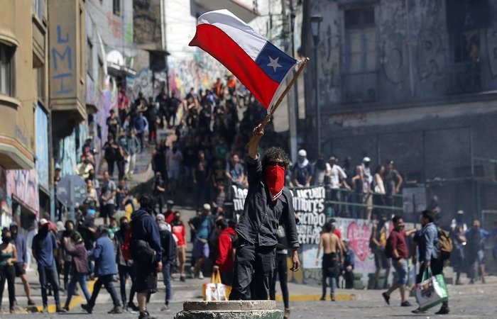 Manifestante ergue a bandeira do Chile em protesto na cidade litornea de Valparaso. (Foto: Javier Torres/AFP)