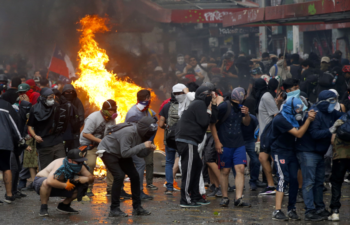 Ao passar diante do Palácio Presidencial, os manifestantes gritaram palavras de ordem contra o Piñera e insultaram os policiais que protegiam o La Moneda (Foto: JAVIER TORRES / AFP) Ao passar diante do Palácio Presidencial, os manifestantes gritaram palavras de ordem contra o Piñera e insultaram os policiais que protegiam o La Moneda (Foto: JAVIER TORRES / AFP)