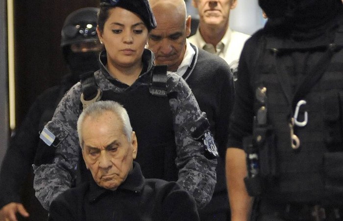 Padres Nicola Corradi (na cadeira de rodas) e Horacio Corbacho (ao fundo, de branco) e ex-jardineiro do Instituto Prvolo Armando Gomez (centro, de suter preto) so escoltados at o julgamento em Mendoza, Argentina. (Foto: Andres Larrovere/AFP
)