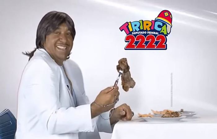 Tiririca fez uma paródia da música - "O Portão" - e da cena, cantando de branco, em frente a um piano e um prato de carne, que "Brasília é seu lugar". (Foto: Reprodução/Youtube)