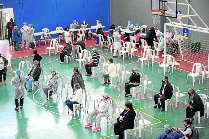 (Vacinação em quadra de esportes na Colômbia: sintomas foram mais comuns em mulheres e em pessoas com menos de 50 anos. Foto: Raul ARBOLEDA/AFp) (Vacinação em quadra de esportes na Colômbia: sintomas foram mais comuns em mulheres e em pessoas com menos de 50 anos. Foto: Raul ARBOLEDA/AFp)