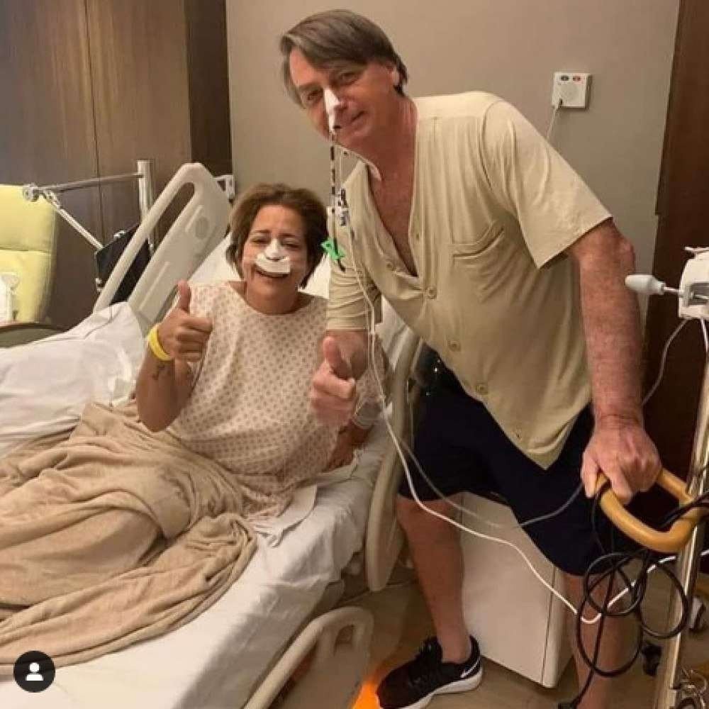 (Uma foto postada nas redes sociais pela primeira-dama, Michelle Bolsonaro, mostra o mandatário de pé, posando ao lado de outra paciente, enquanto se apoia em um suporte de sonda. Foto: Reprodução / Redes Sociais) (Uma foto postada nas redes sociais pela primeira-dama, Michelle Bolsonaro, mostra o mandatário de pé, posando ao lado de outra paciente, enquanto se apoia em um suporte de sonda. Foto: Reprodução / Redes Sociais)