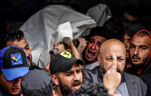 Enlutados carregam o cadáver de uma das pessoas que morreram quando seu barco virou um dia antes na costa de Trípoli, no necrotério de um hospital da cidade do norte do Líbano. (Ibrahim CHALHOUB / AFP )
