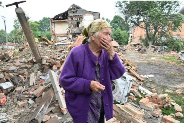 Raisa Kuva, 82 anos, chora diante de prédio destruído em bombardeio à cidade de Chuguiv, a leste de Kharkiv (crédito: Sergey Bobok/AFP)