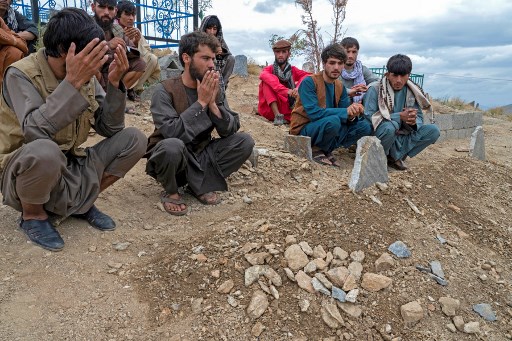 Afegos rezam em tmulos de vtimas, aps cerimnia de enterro em um cemitrio nos arredores de Cabul, em 18 de agosto de 2022. O nmero de mortos em uma exploso que atingiu uma mesquita lotada de fiis na capital afeg, Cabul, em 17 de agosto, subiu para 21, disse a polcia. -  (Foto: WAKIL KOHSAR / AFP)