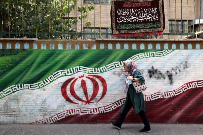 Iraniana caminha diante de mural, em Teer: nova lei deve reforar a represso pelo uso de vestimentas  (Atta Kenare/AFP)
