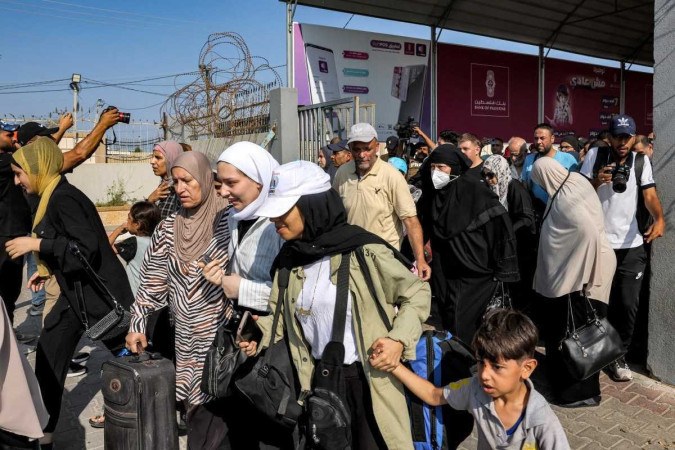 Pessoas atravessam um porto para entrar na passagem de fronteira de Rafah para o Egito, no sul da Faixa de Gaza, em 1 de novembro de 2023 (Crditos: MOHAMMED ABED / AFP)