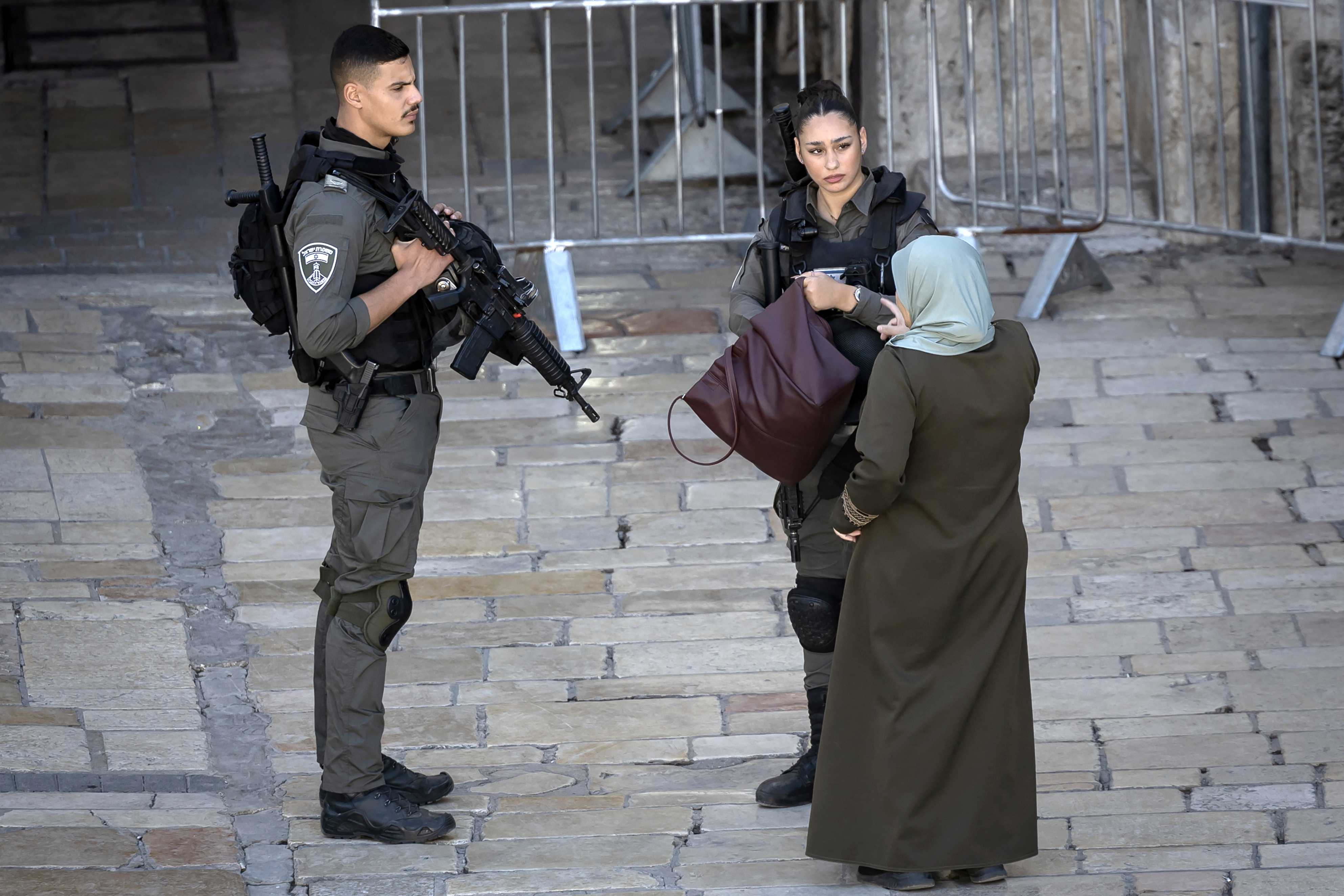 Uma oficial de segurança israelense verifica a bolsa de uma mulher palestina na entrada do Portão de Damasco depois que uma componente das forças de segurança israelenses foi ''gravemente'' ferida em um ataque com faca na área (Créditos: Fadel Senna / AFP)